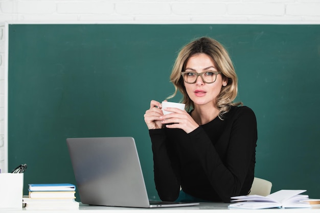 Portrait of female teacher teaching drinking coffee in classroom on blackboard