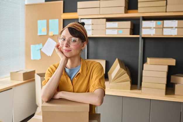 Portrait of female warehouse worker looking at camera while packing parcels in storage