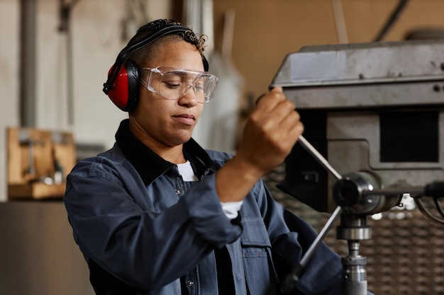 Portrait of female worker operating machine units in industrial workshop copy space