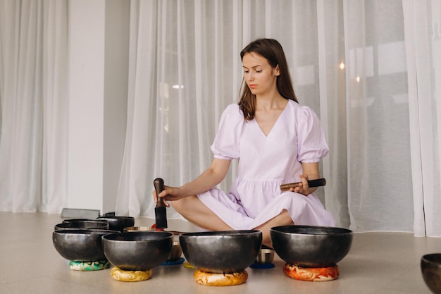 Portrait of a female yoga teacher playing a Tibetan bowl or singing a bell in the gym during a yoga retreat