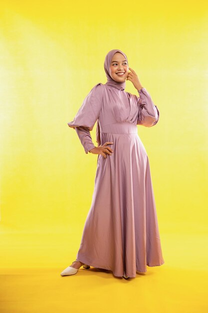 Portrait of feminine asian muslimah wearing pink dress on yellow background