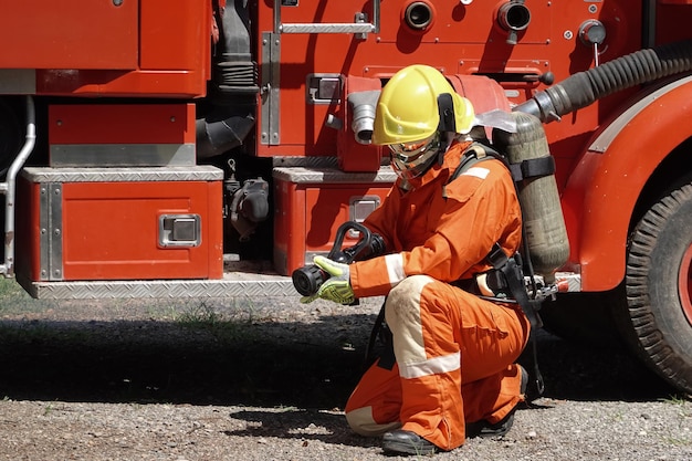 Portrait of a firefighter wearing a firefighting suit with equipment water truck background