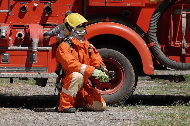 Portrait of a firefighter wearing a firefighting suit with equipment water truck background