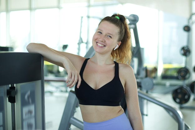 Portrait of fit athletic young woman in gym fitness trainer coach