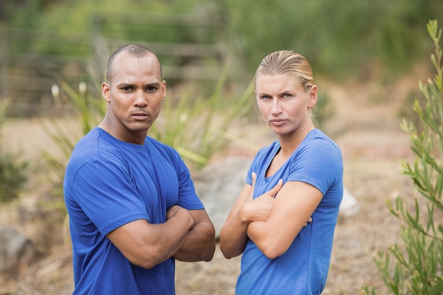 Portrait of fit man and woman standing with arms crossed during boot camp training