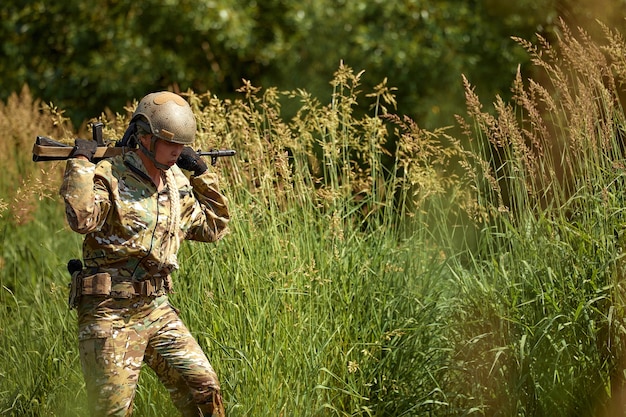 Portrait of fit military female holding weapon rifle in hands in river posing alone Confident strong athlete lady looking at side seriously Attractive goodlooking female in military gear