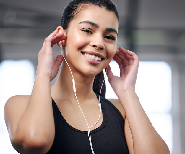 Portrait of a fit young woman using earphones at the gym