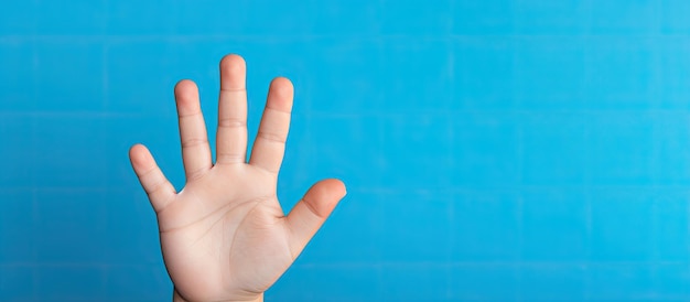 Portrait of a five year old boy displaying five fingers on a blue background with empty space