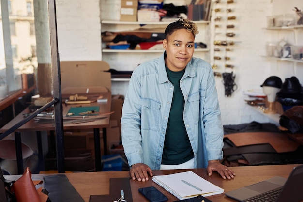 Portrait of fmodern young woman smiling at camera while posing in leatherworking workshop female sma