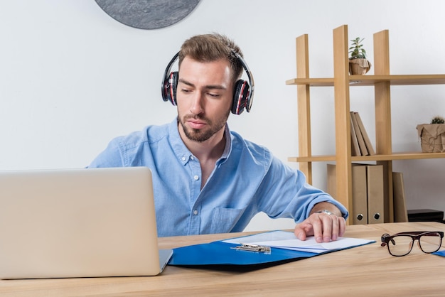 Portrait of focused businessman working with documents and laptop in office