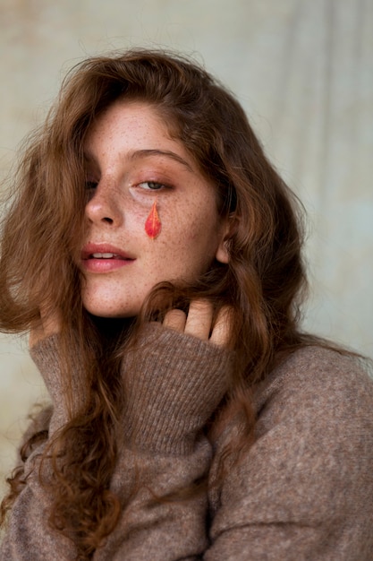 Portrait of freckled woman with leaves on her face