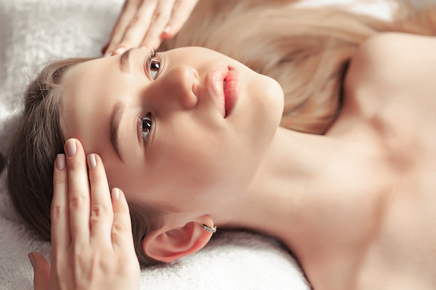 Portrait of fresh and beautiful brunette woman taking face massage