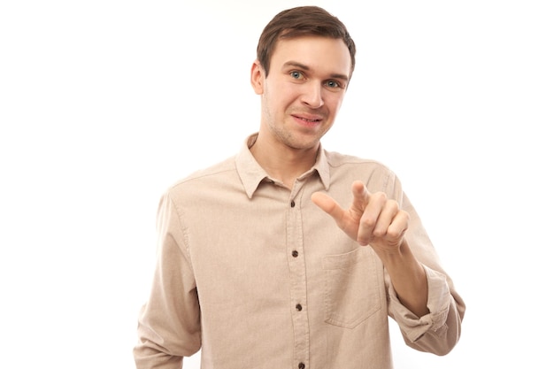 Portrait of friendly positive young male chooses you points finger at the camera isolated on white background