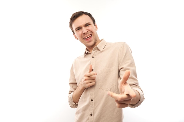 Portrait of friendly positive young male chooses you points finger at the camera isolated on white background