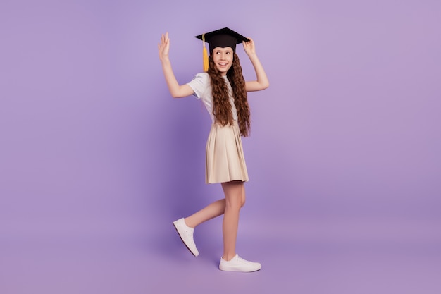 Portrait of friendly student girl walk college education concept wave hand blank space on purple background