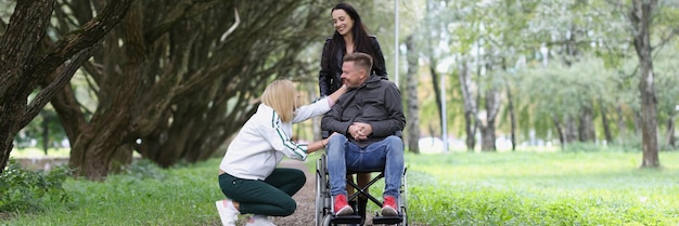 Portrait of friends walking with man in wheelchair in park disability and healthcare concept