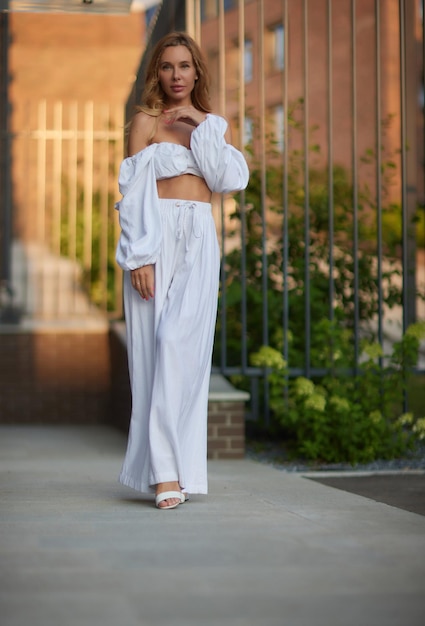 Portrait from back of elegant girl with long curly hair walking on steer on old building background