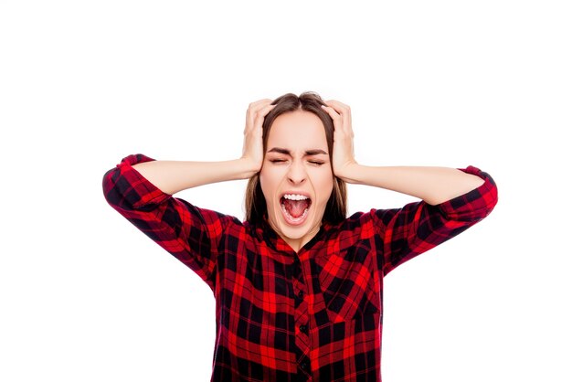 Portrait of frustrated angry young woman touching head and screaming