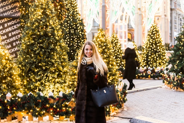 Portrait in full growth, Russian beautiful woman in a mink coat on the Red Square in Moscow in Christmas time