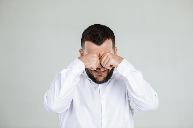 Portrait of funny bearded man is crying and wiping tears