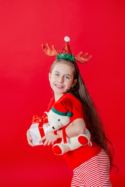 Portrait of a funny cheerful girl with bandage of horns on her head hugging isolated red background