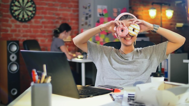 Photo portrait of funny creative woman with donut eyes smiling at camera working in office