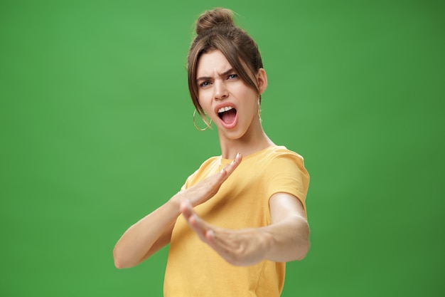 Photo portrait of funny and emotive charismatic young woman standing in martial arts pose, showing fighting skills yelling kiya, open mouth frowning making karate movements.