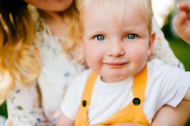 Portrait of funny lovely little boy in mom's arms