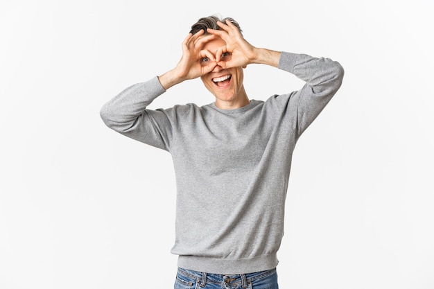 Portrait of funny middle-aged guy making faces, showing hand glasses around eyes