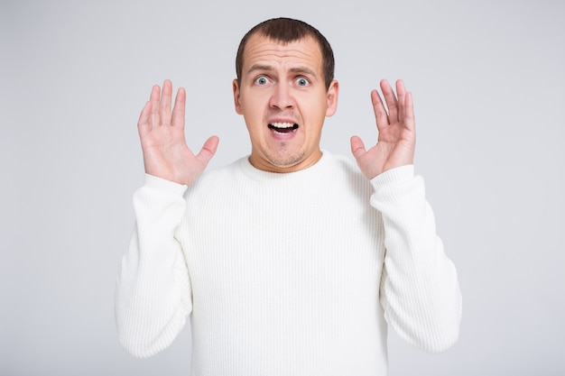 Portrait of funny surprised man shouting about something over gray background