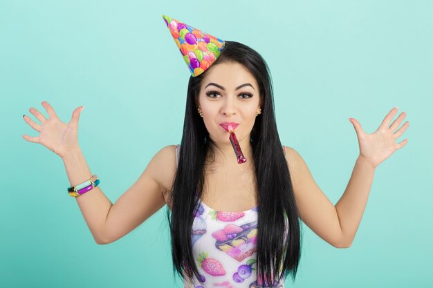 Portrait of funny woman in birthday hat and pink shirt on blue