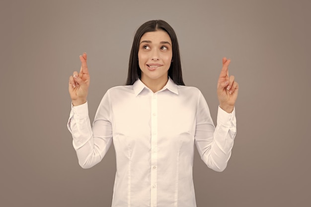 Portrait of funny woman with crossed fingers for good luck isolated background Headshot of glad woman crosses fingers with positive expression believes in good luck and success Positive thinking