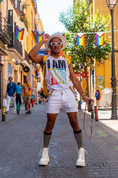 Portrait of a gay black ethnic man at the pride party taking photos with a hat LGBT flag