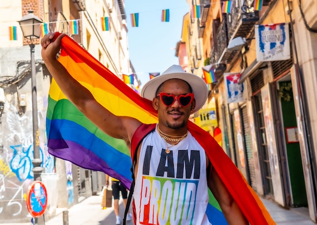 Portrait of a gay black man walking at the pride party with an LGBT flag