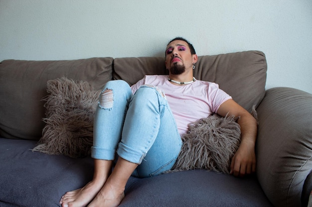 Portrait of a gay man in makeup sad unhappy at home