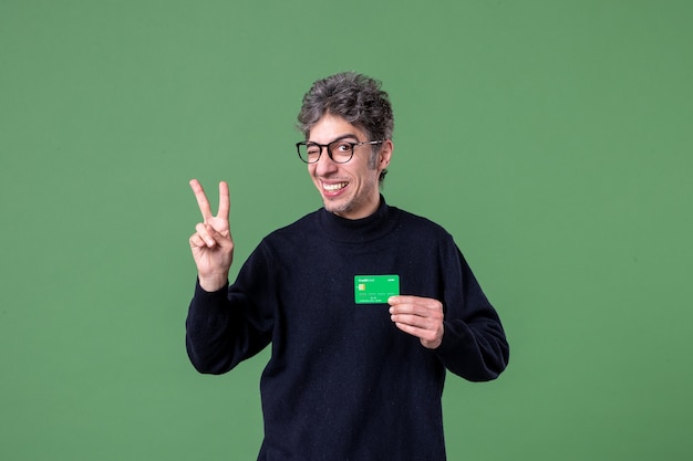 Portrait of genius man holding credit card in studio shot green wall