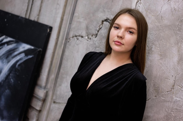 Portrait of a girl against the background of a textured wall next to a painting concept of