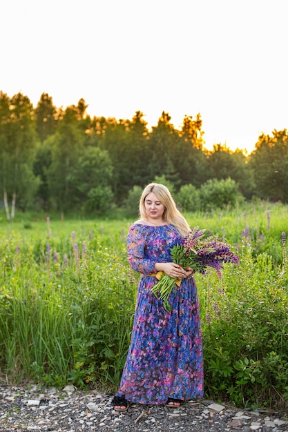 Portrait of a girl in a blooming field in the sun at sunset