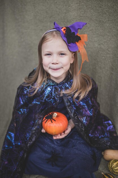 Photo portrait of a girl in carnival clothes for halloween with pumpkin