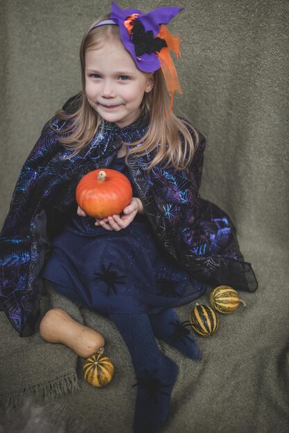 Photo portrait of a girl in carnival clothes for halloween with pumpkin