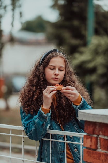 A portrait of a girl eating pizza on a lunch break at school during the gradual opening after the closure of the pandemic Selective focus High quality photo