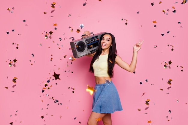 Portrait of girl hold boombox showing vsign isolated over pink wall