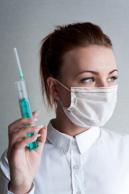 Portrait of a girl in a medical mask Holding a syringe in her hand Close upxA