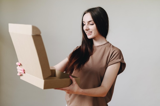 Portrait of a girl in ordinary life and an open cardboard box on the wall looks into the box