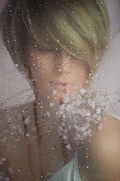 Portrait of a girl on a pink background with flowers Tenderness and feminine The sphere of beauty and women's health Short haircut blonde hair