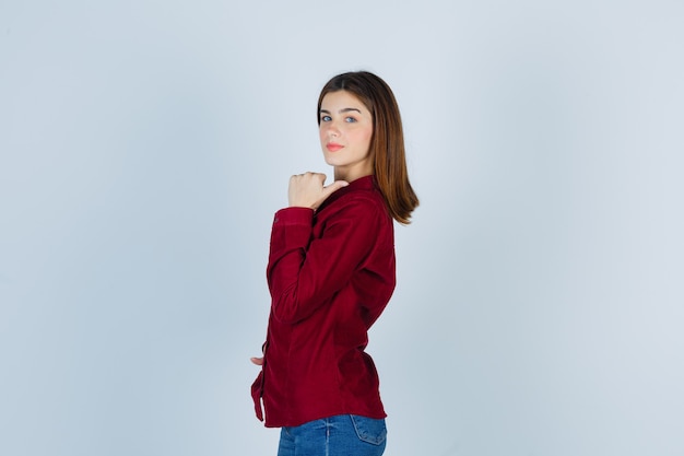 Portrait of girl pointing back with thumb in casual shirt and looking confident