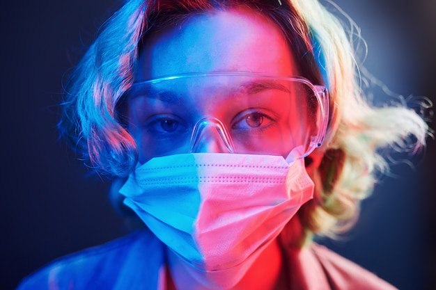 Portrait of girl in protective glasses and mask in neon lights