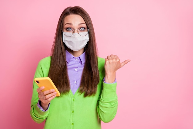 Portrait girl use smartphone point thumb finger copyspace covid-19 news wear medical mask isolated pastel color background