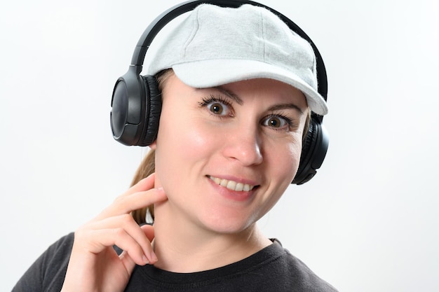 Portrait of a girl on a white background with wireless headphones and a cap on her head copy space with emotional photo of a girl with headphones