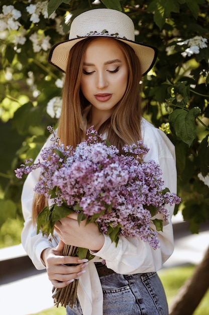 Portrait of a girl with a bouquet of lilacs. summer makeup. summer walk in the park